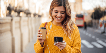 A woman smiles as she looks at her smartphone