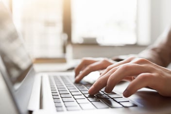 Fingers typing on laptop keyboard