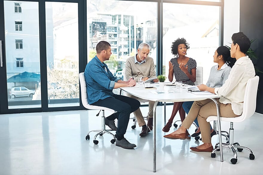 5 business professionals having a lively discussion at a table in the office 